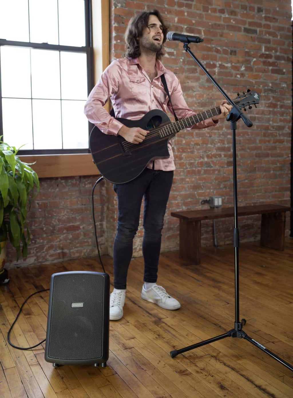 Microphone boom stand with boom arm near guitarist, tripod base