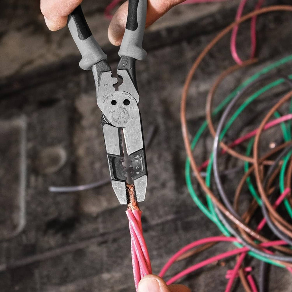 Hand using hybrid multitool pliers to strip wires with exposed copper ends