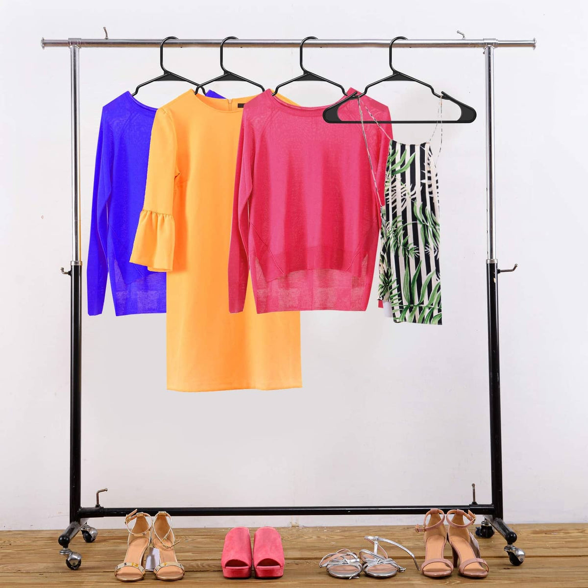 Multiple black plastic clothes hangers on a metal garment rack with shirts