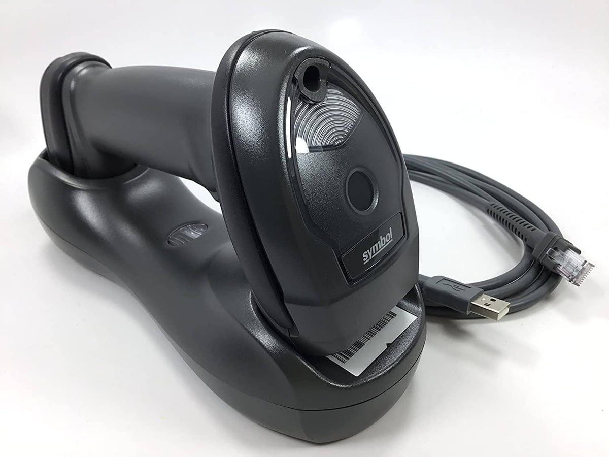 Black wireless barcode scanner docked on charging cradle; visible scan window and cable