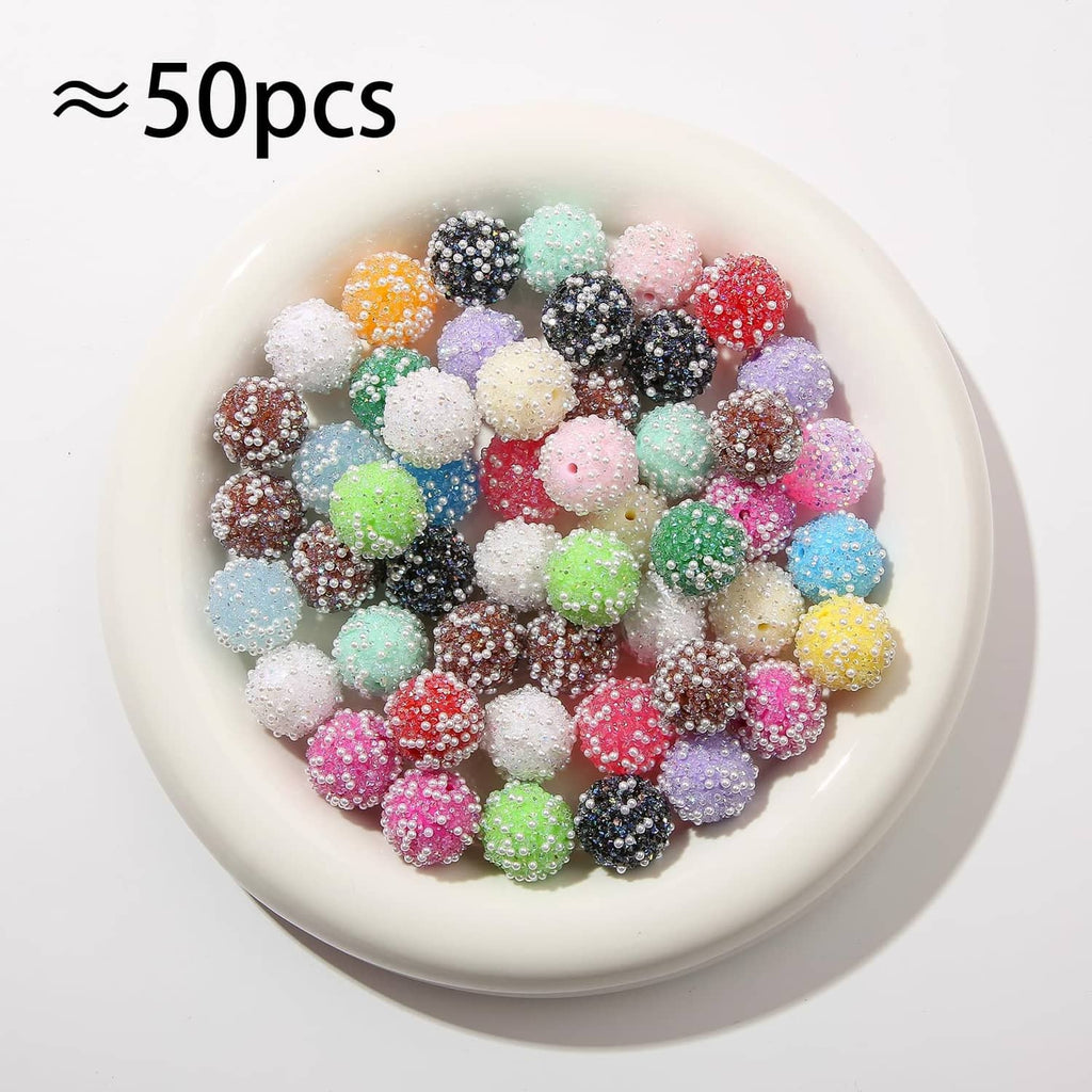 ≈50 pcs of acrylic round rhinestone beads in assorted colors in a white dish