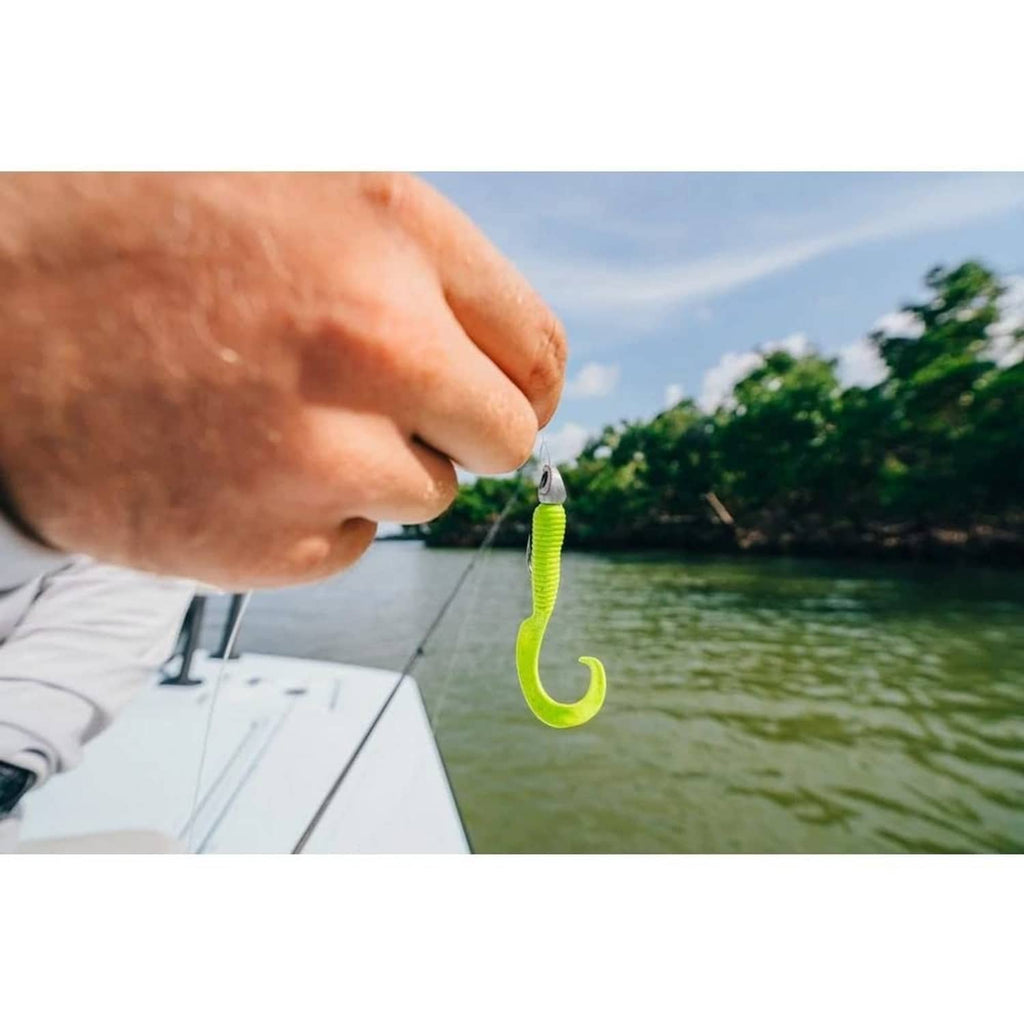 Bright green ribbed soft fishing bait on a hook held over water