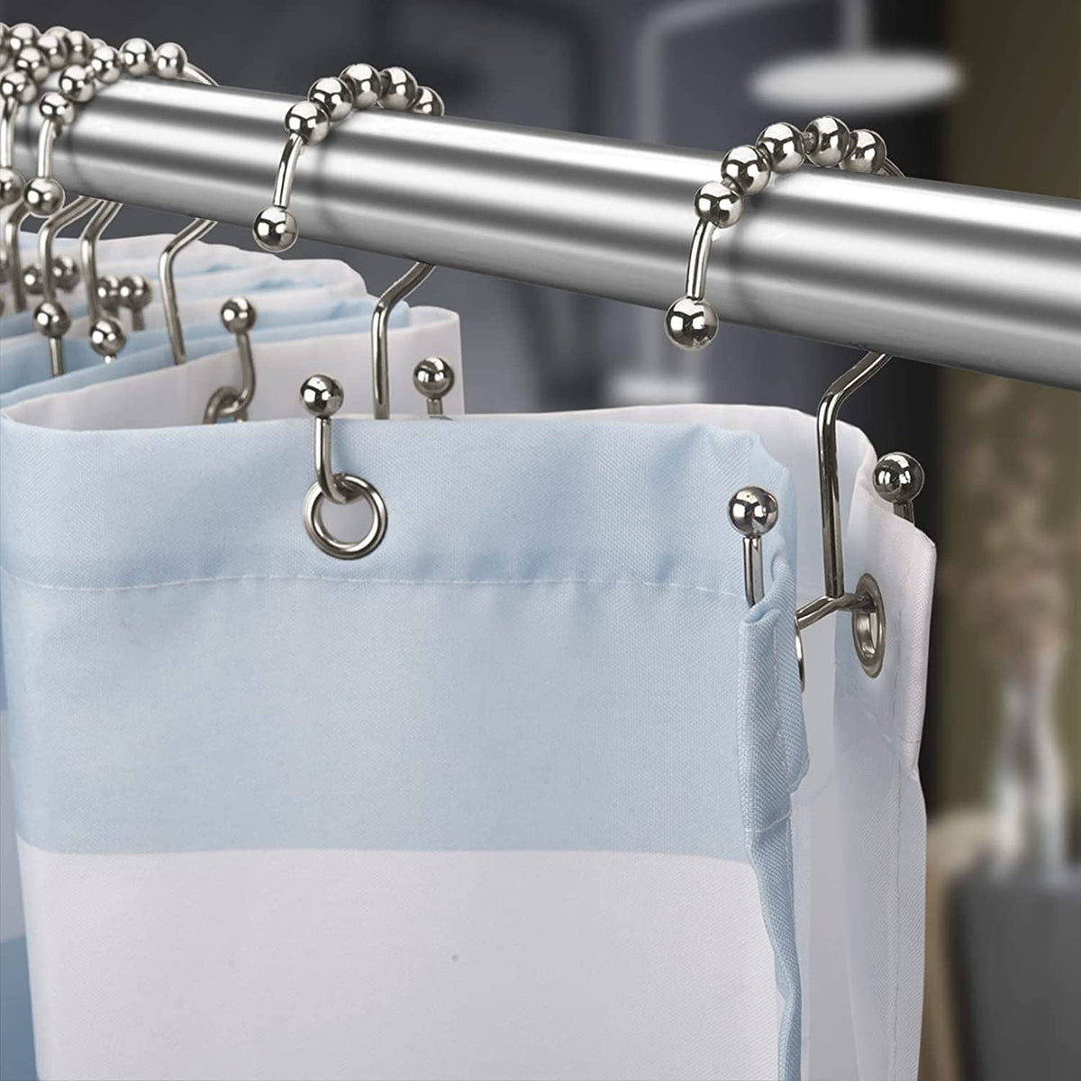 Blue shower liner attached to chrome shower curtain hook rings with ball stops