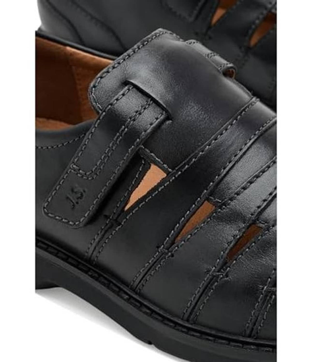 Black leather shoe detail: strap closure, stitching, and textured outsole edge