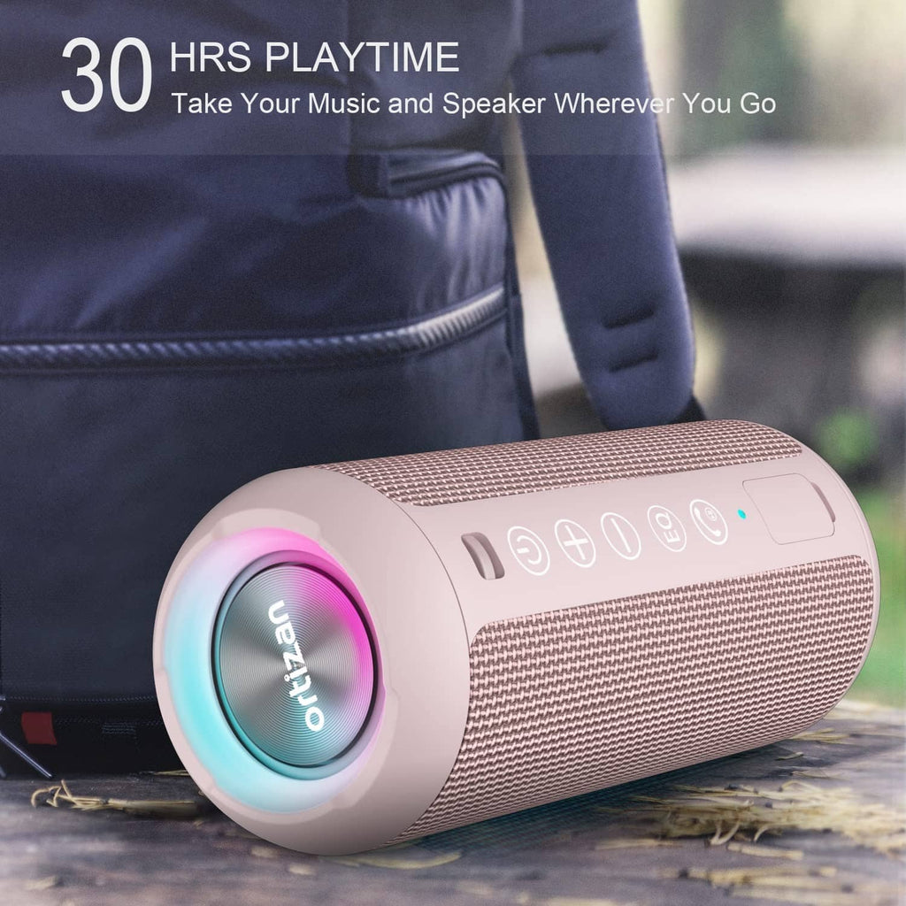 Pink portable Bluetooth speaker with glowing light ring, placed on outdoor ground