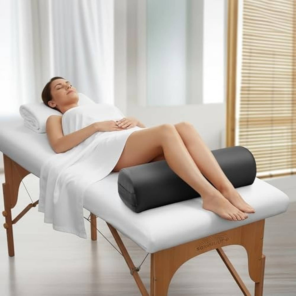 Black massage table bolster pillow placed under a lying client's legs
