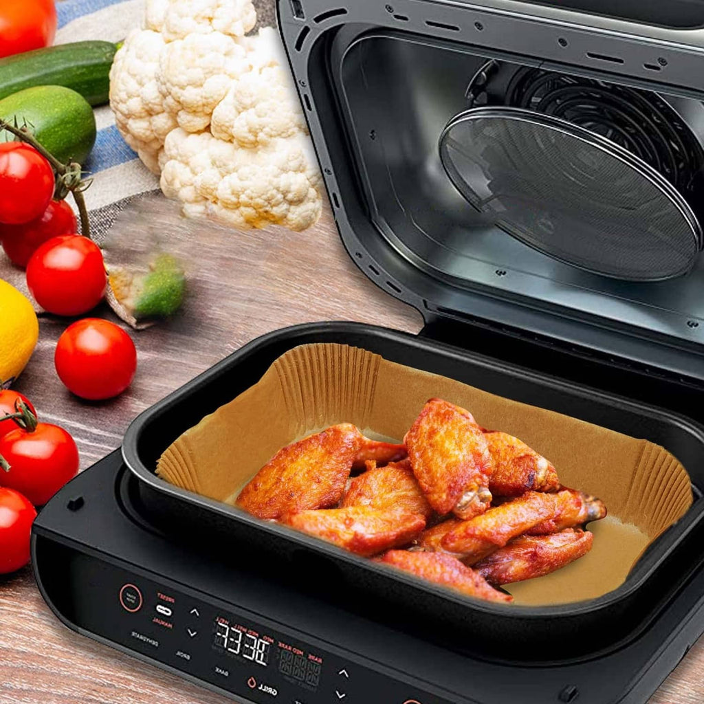 Brown rectangular air fryer liner holding chicken pieces inside the air fryer basket