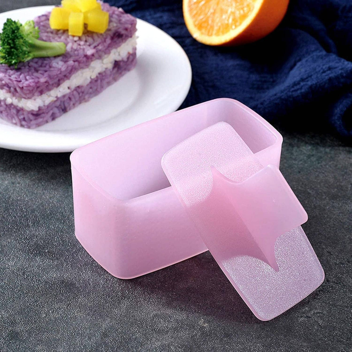 Pink onigiri mold tray with sliding inner piece and ridged press insert