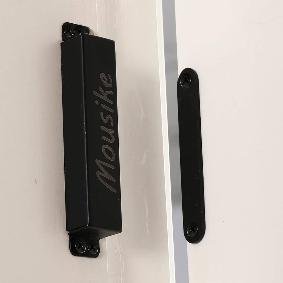 Black magnetic door catch installed on door edge with screw-mounted latch bar