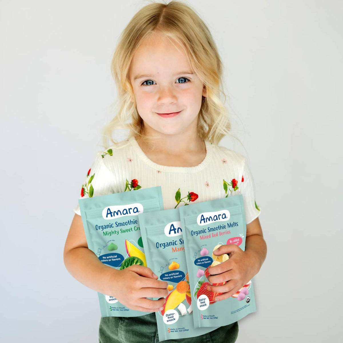 Toddler holding Amara organic smoothie melts variety pack pouches