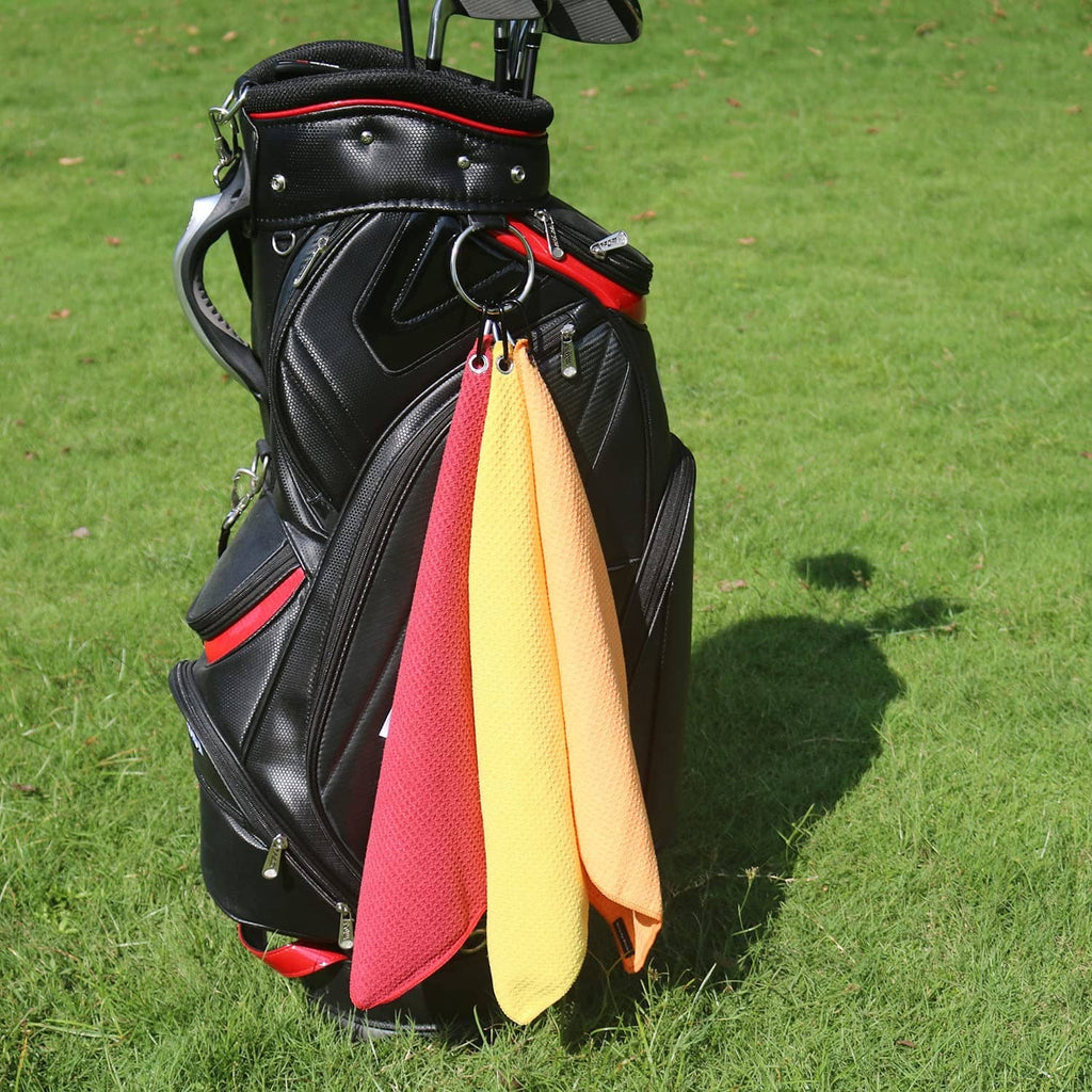 Microfiber golf towels hanging from a golf bag: red, yellow, and orange rolled