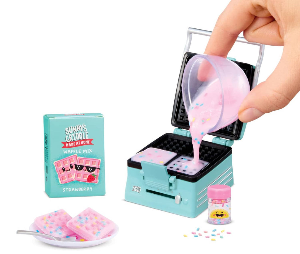 Mini waffle maker appliance with open lid, pink batter, and waffle mix pieces