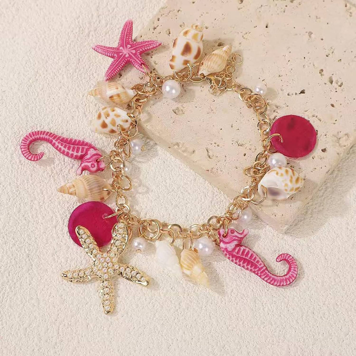 Colorful seahorse and starfish charm bracelet with shell beads and faux pearls on gold chain.