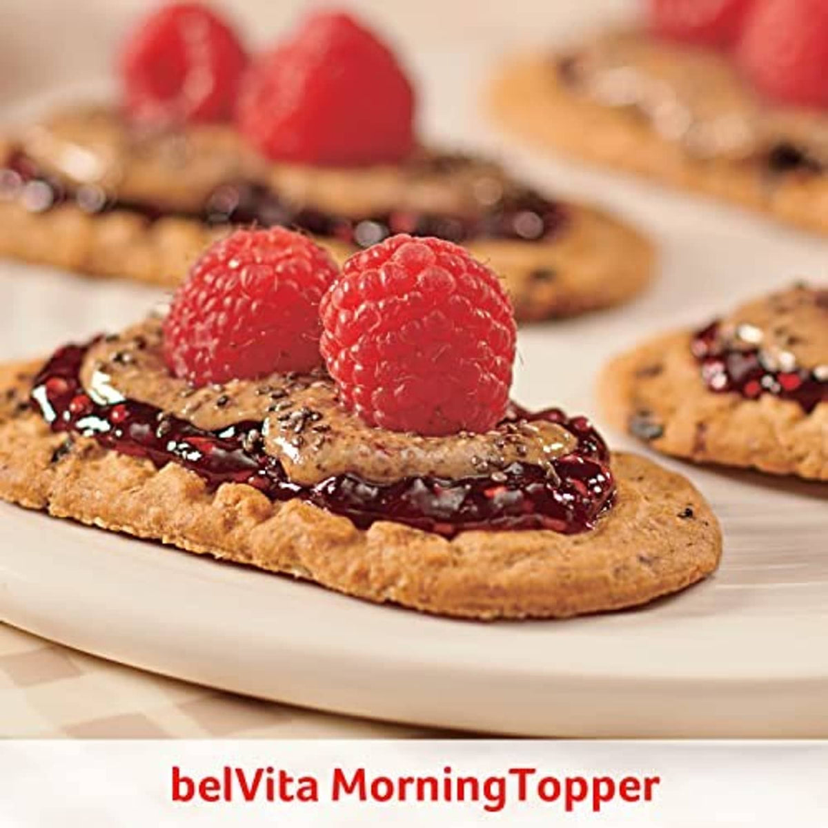 Biscuit topped with dark jam, whole cranberries, and two raspberries on a plate