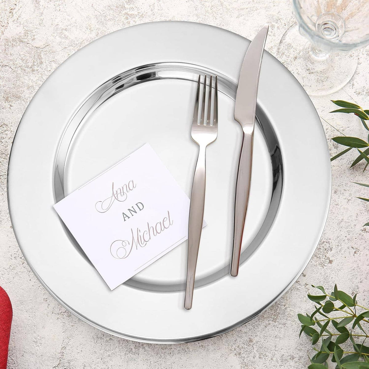Round silver stainless steel charger plate with place card and fork and knife