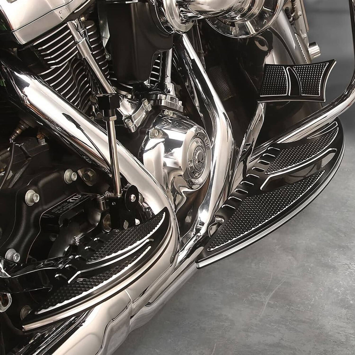 Mounted black textured motorcycle floorboard with silver accent on the side panel