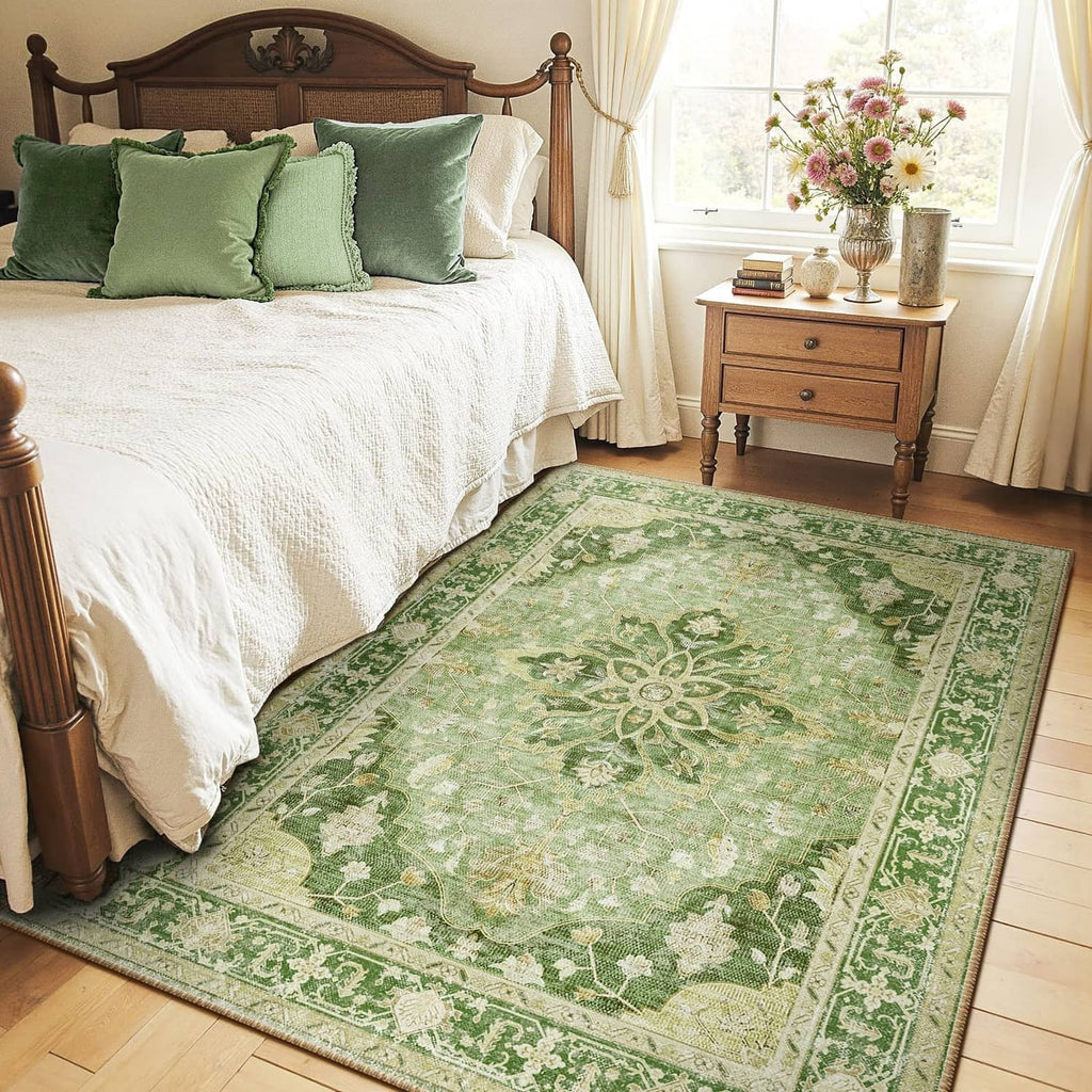 Rectangular green ornamental area rug with cream border pattern beside a bed