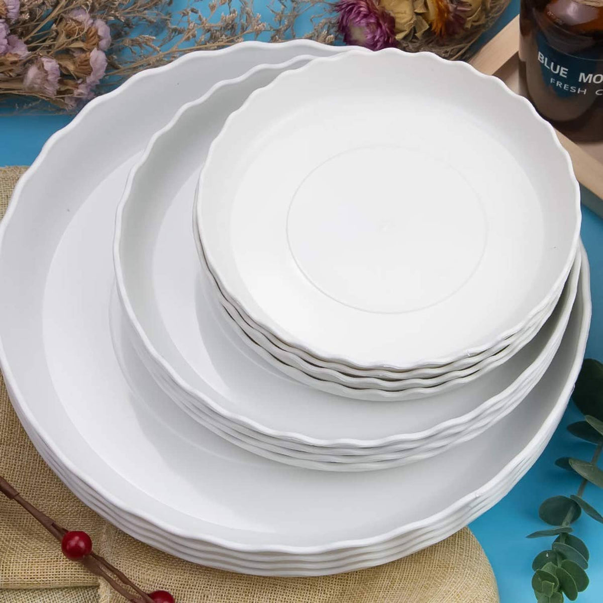 Nested stack of white round plastic plates with wavy scalloped rims
