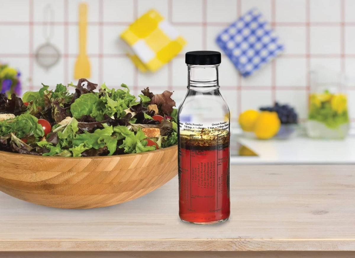 Glass salad dressing bottle with black cap, red dressing inside