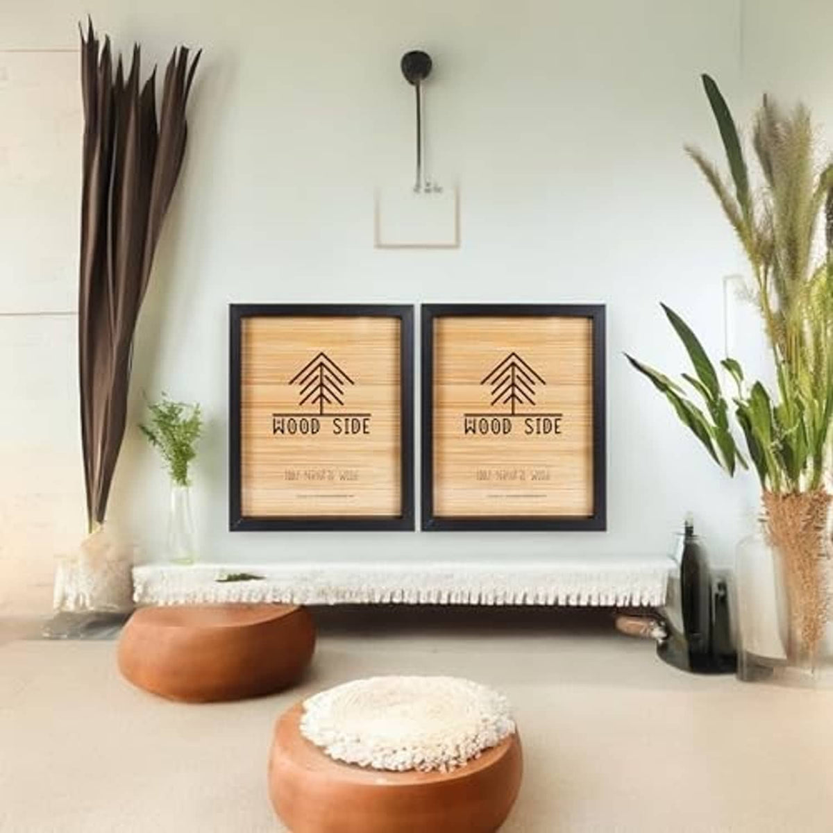 Two black wooden poster frames with “Wood Side” prints above a bench and decor