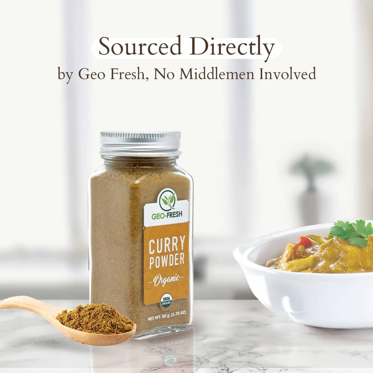 Organic curry powder jar with wooden spoon and a bowl of prepared curry