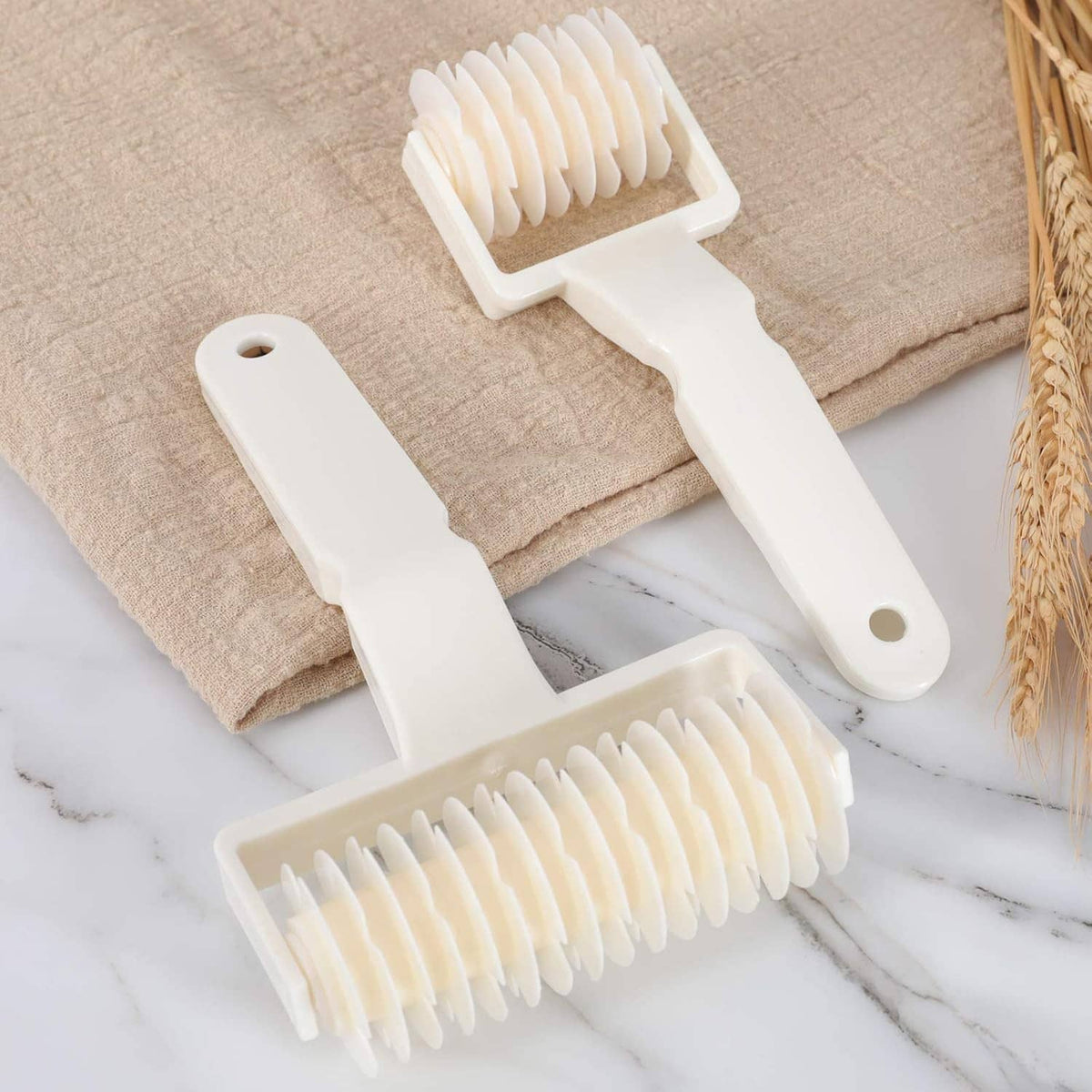 Lattice dough roller cutter set with cream ridged rollers on dough and towel