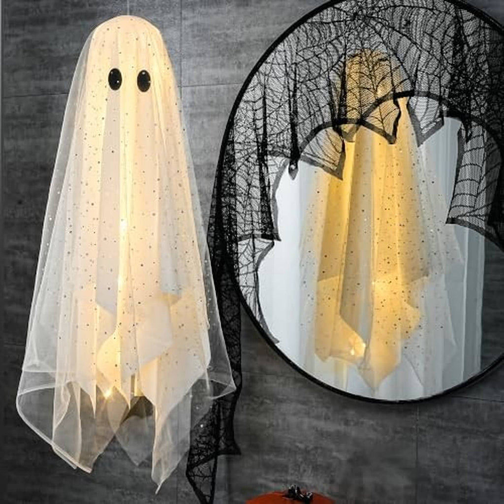 White and warm-lit hanging ghost decoration with black eyes and sheer veil beside a net