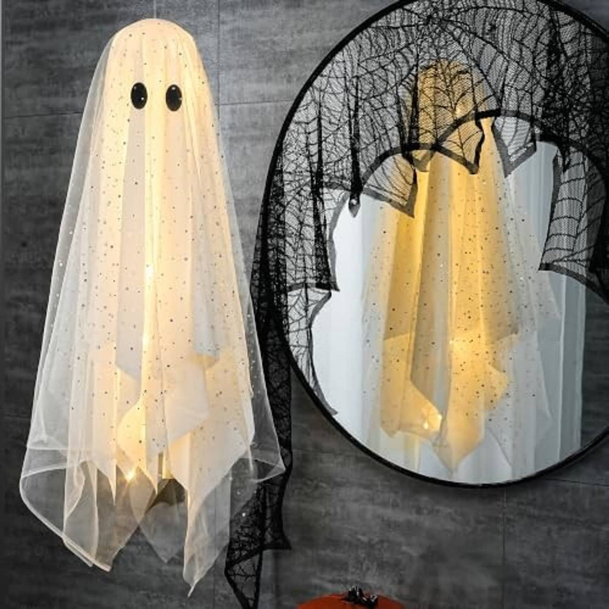 White and warm-lit hanging ghost decoration with black eyes and sheer veil beside a net