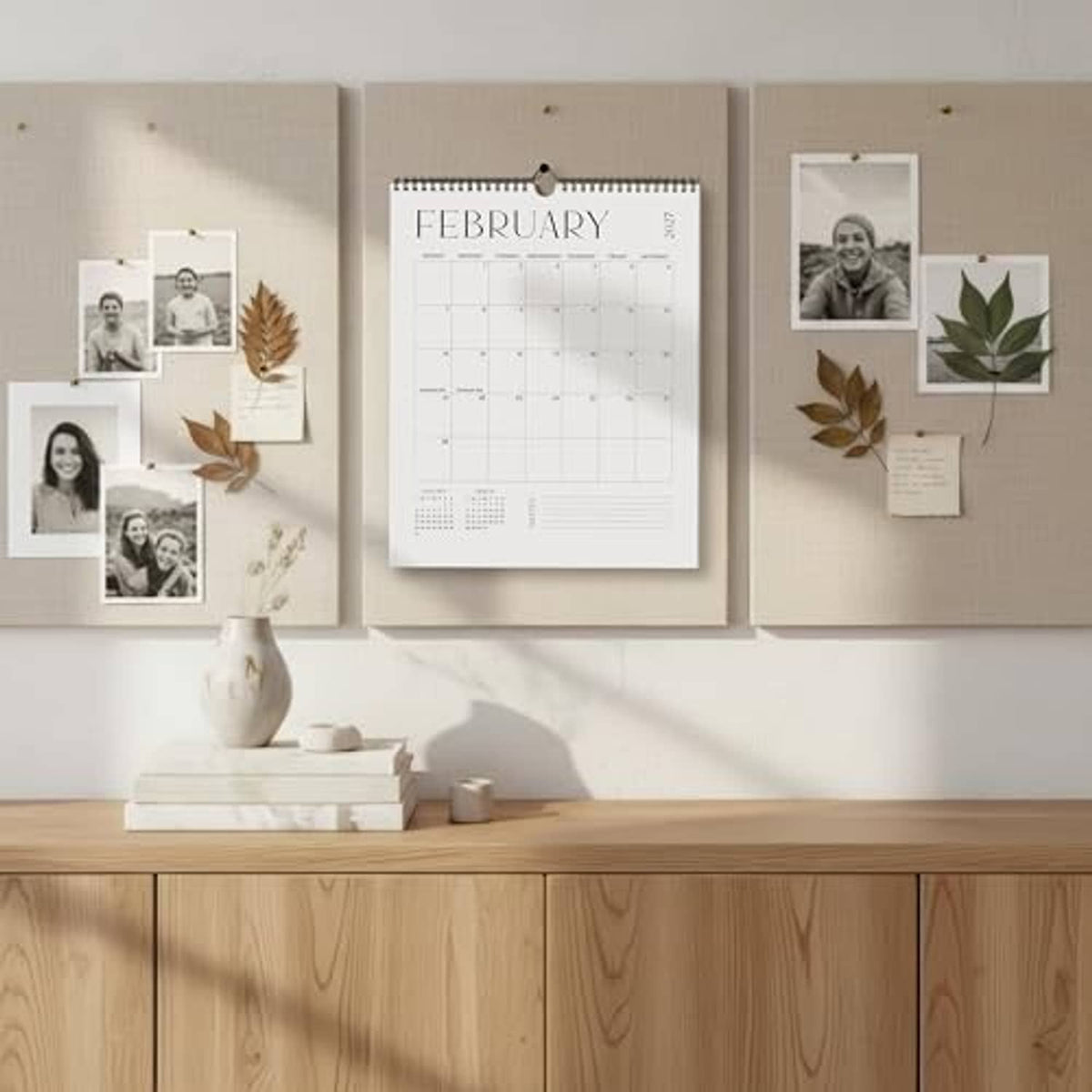February wall calendar with spiral binding on beige wall among pinned photo cards