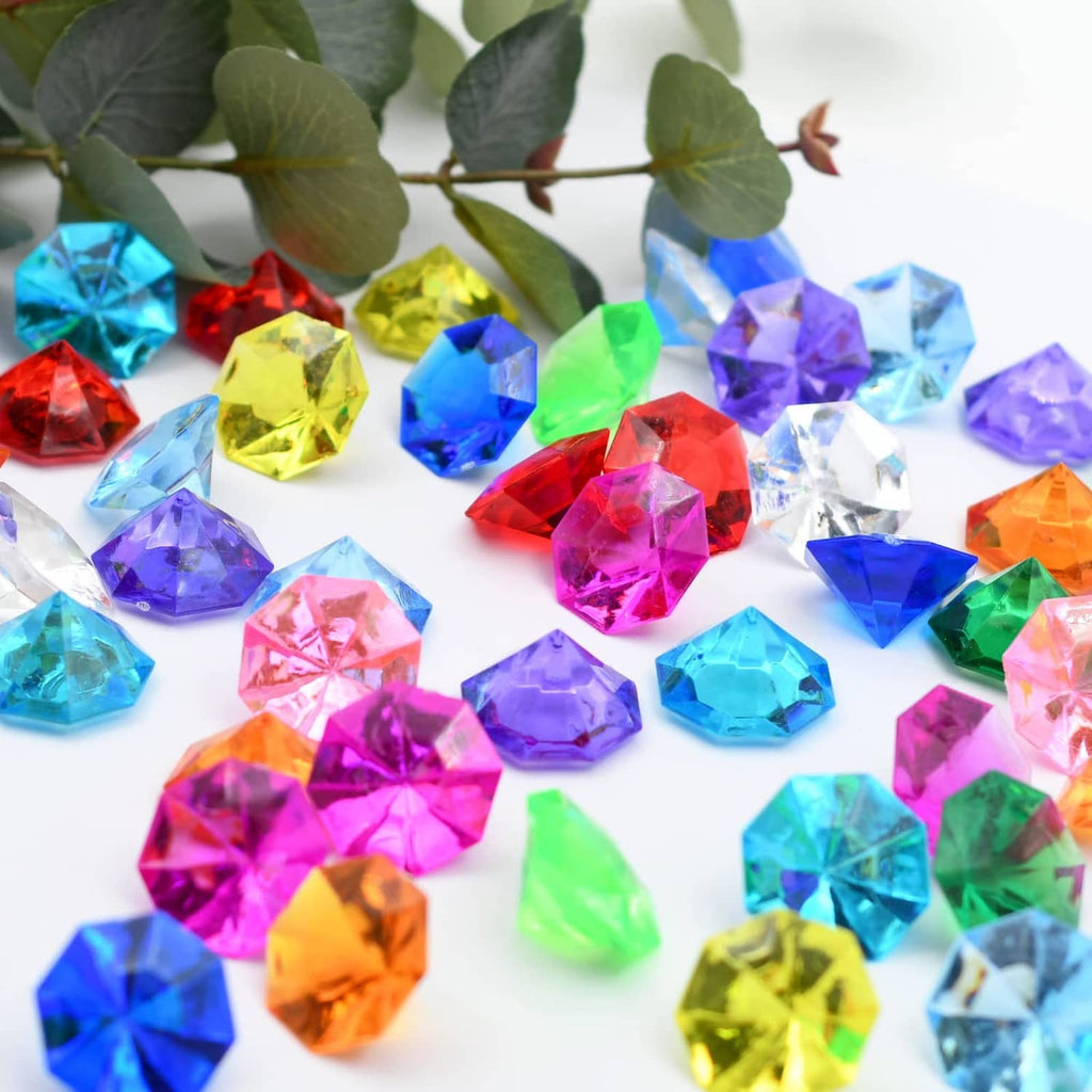 Assorted multicolor faceted acrylic diamond gems scattered across a surface