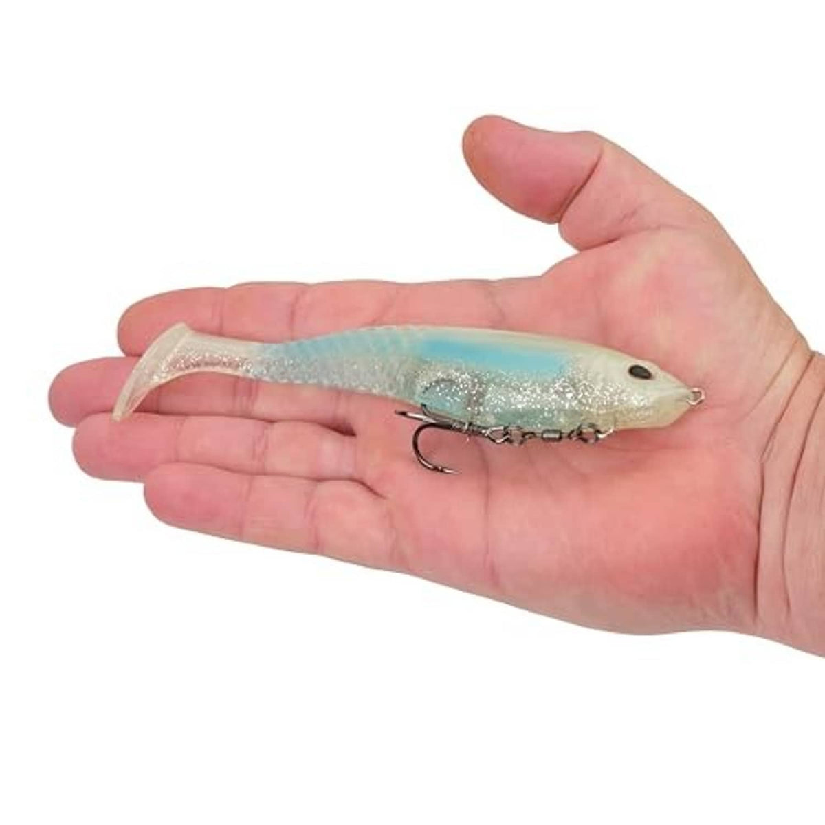 Soft plastic swim bait resting in open hand, teal-silver shad style