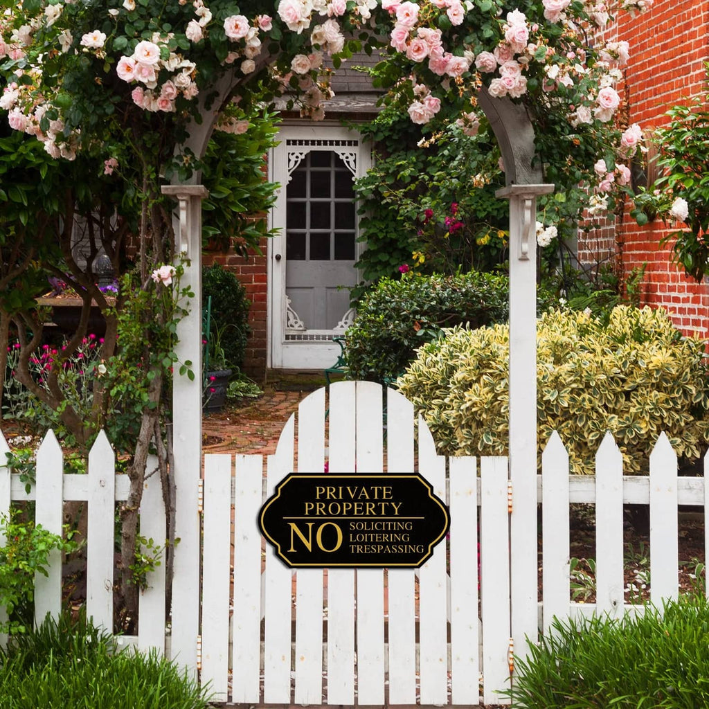 Black private property no trespassing yard sign on pointed stake in a landscaped yard