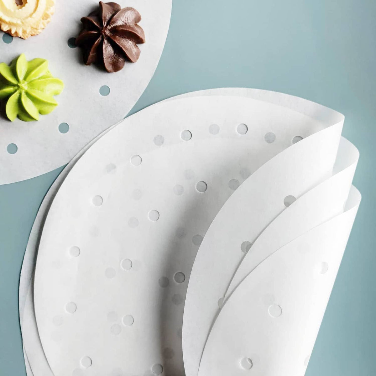 Overlapping round white air fryer parchment liners with evenly spaced holes