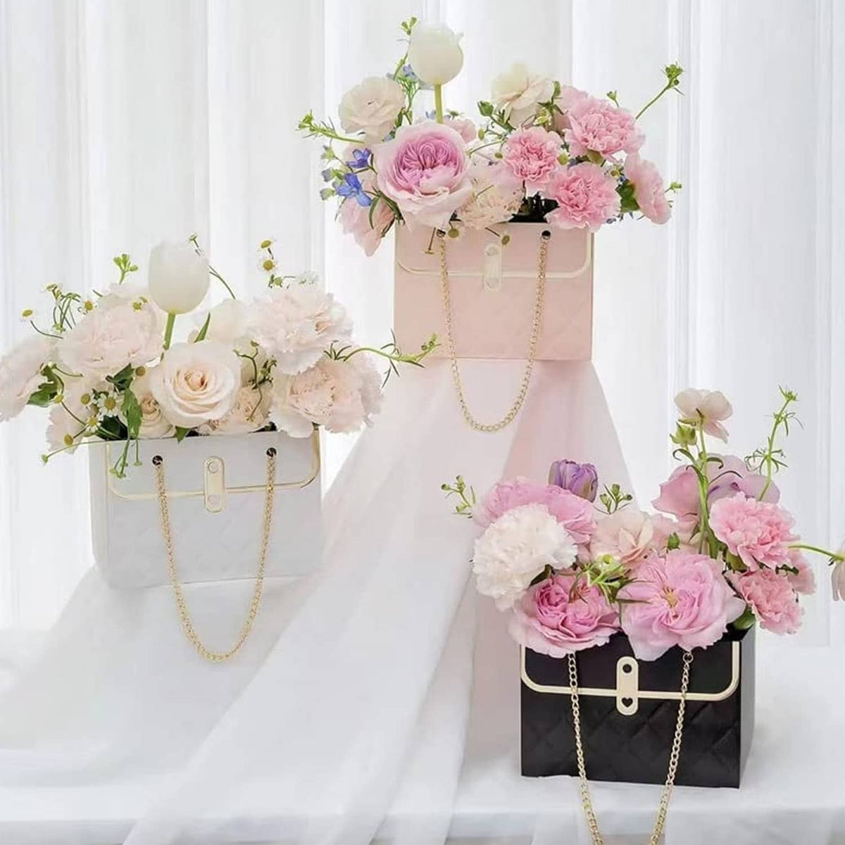 Quilted paper bouquet bags in white, pale pink, and black with gold chain handles
