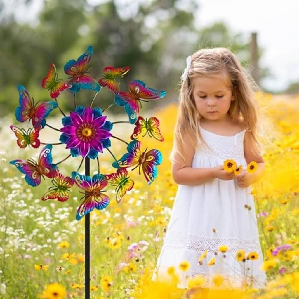 Colorful butterfly wind spinner in a flower garden, with a child beside the stake