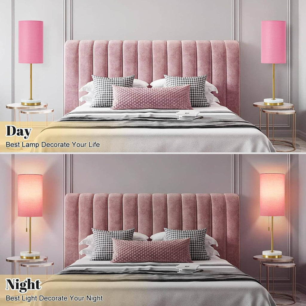 Two minimalist table lamps with pink shades, gold stems, and round white bases.