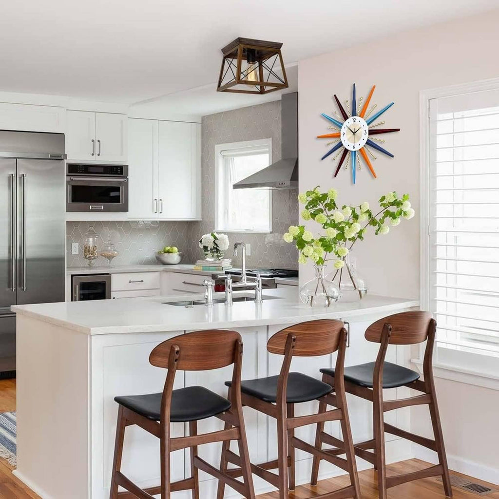 Starburst wall clock with multicolor rays and white dial mounted in a kitchen.