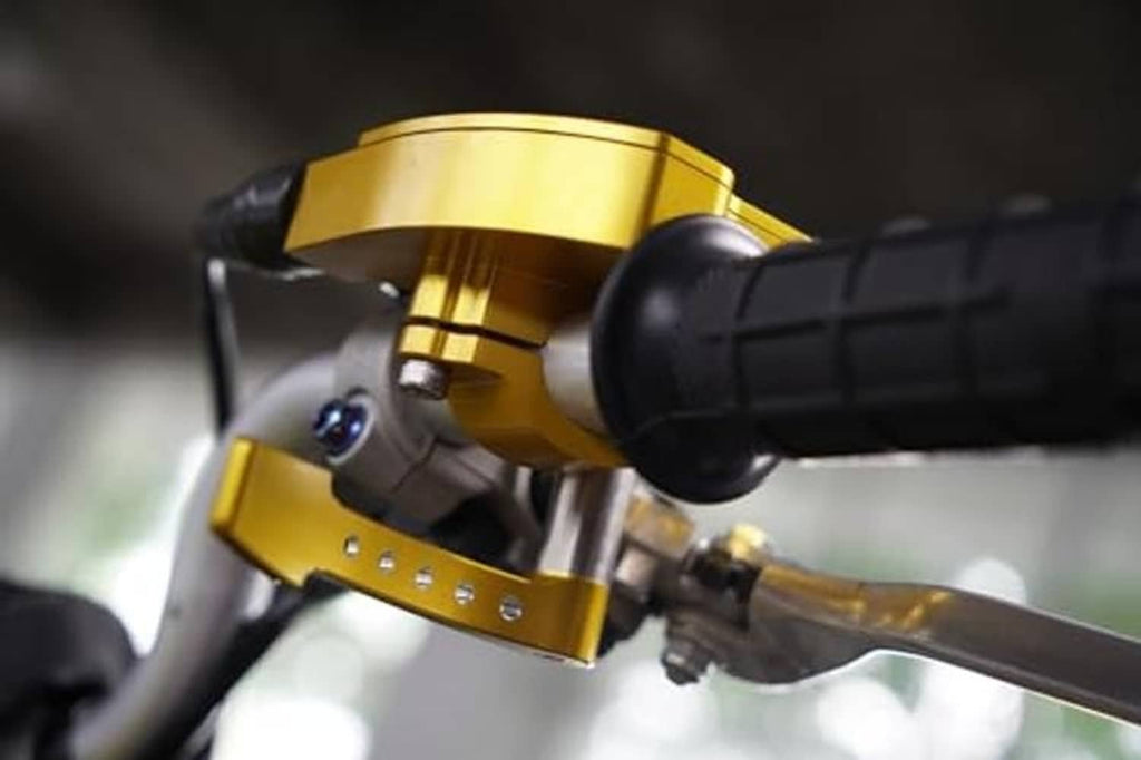 Gold thumb throttle with black grip and control housing on handlebar