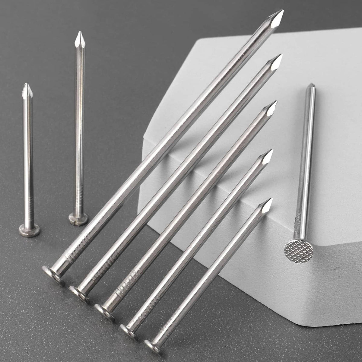 Stainless steel flat head nails with sharp tips laid out with a metal backing plate
