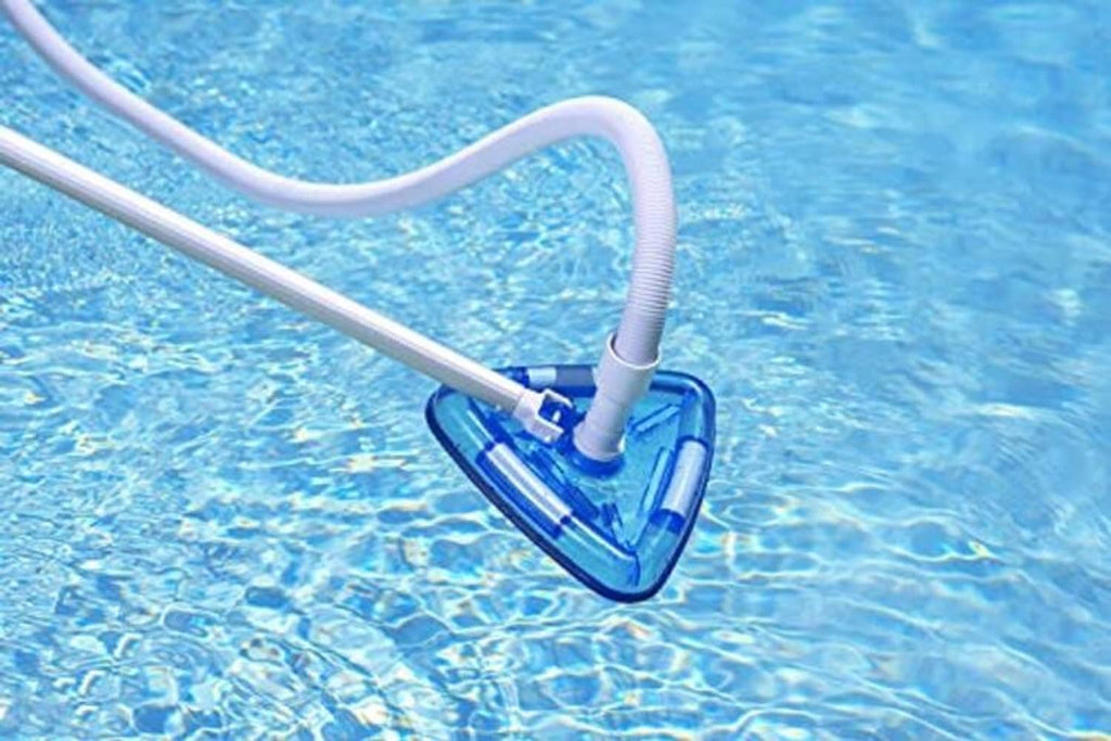 Triangle pool vacuum head floating in pool water with connected hose and pole