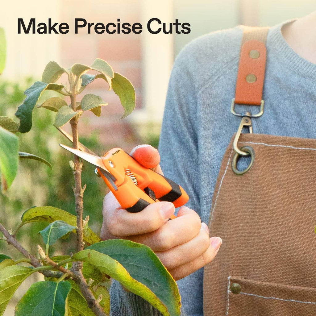 Orange pruning shears held in hand trimming small branches on a leafy plant