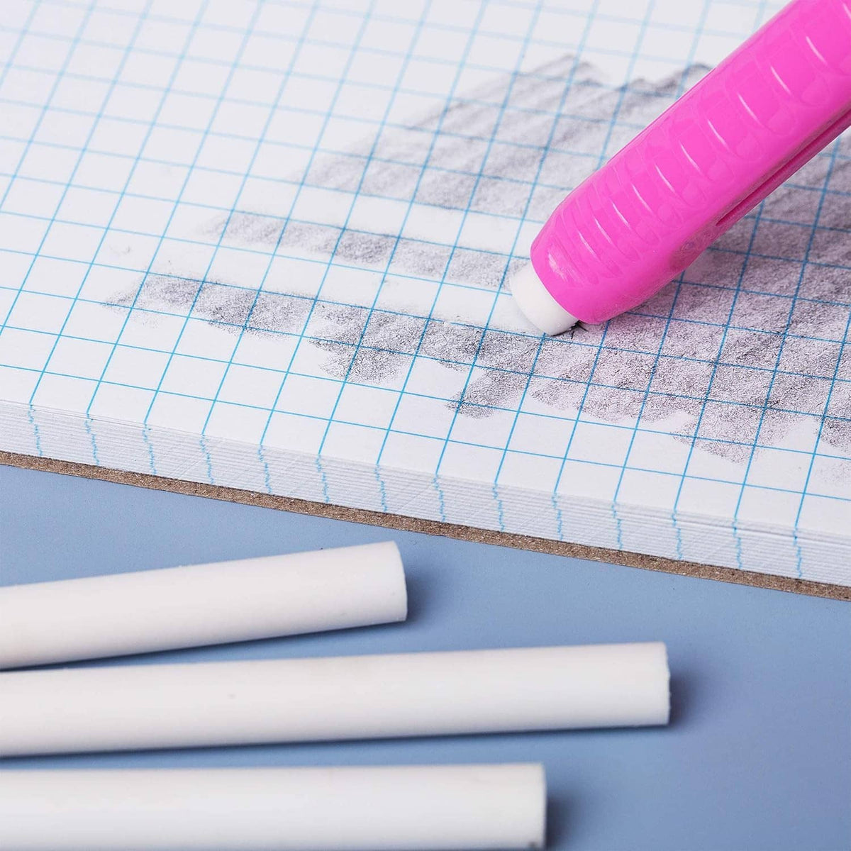 White eraser refill sticks with a purple retractable pen on graph paper