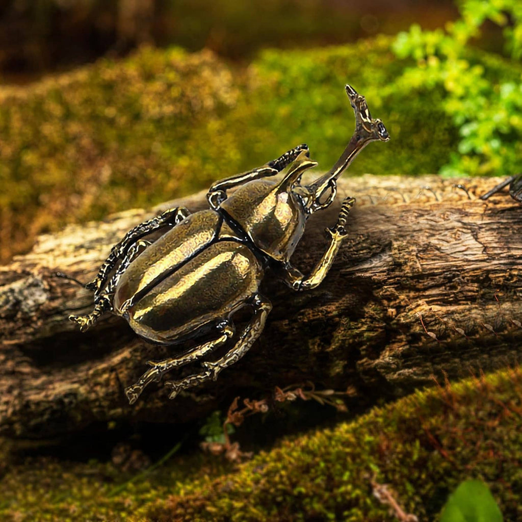 Brass beetle figurine ornament on a small log outdoors