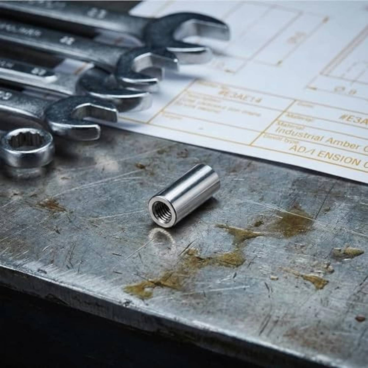 Stainless steel M6 threaded coupling sleeve pieces on a metal work surface