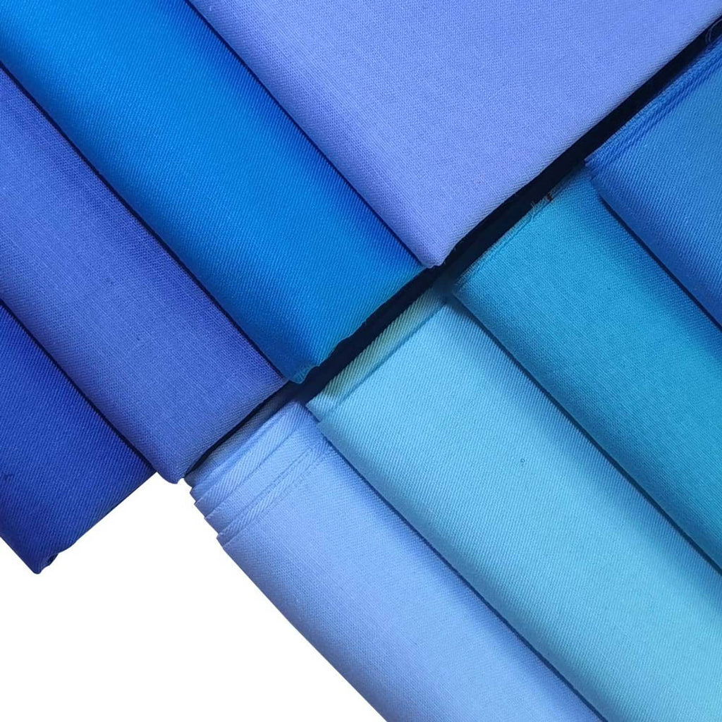 Stacked solid cotton fabric pieces in blue tones, showing fold edges