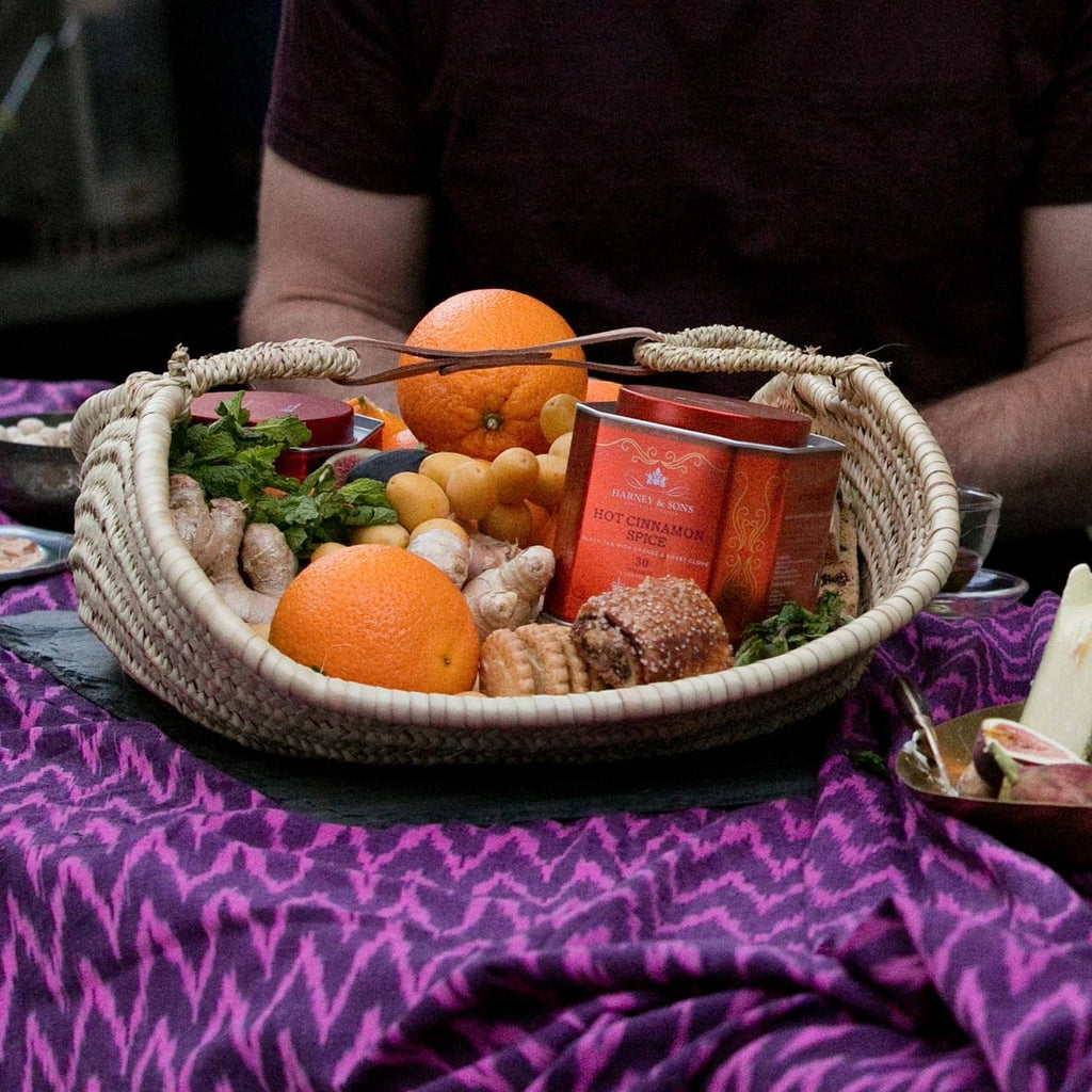 Orange Hot Cinnamon Spice tea tins in wicker basket with oranges and herbs