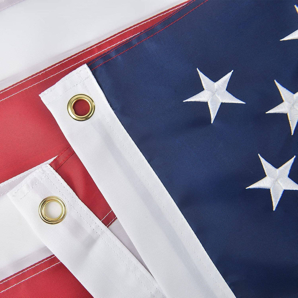 US flag with red-and-white stripes and blue field, showing brass grommets for hanging.