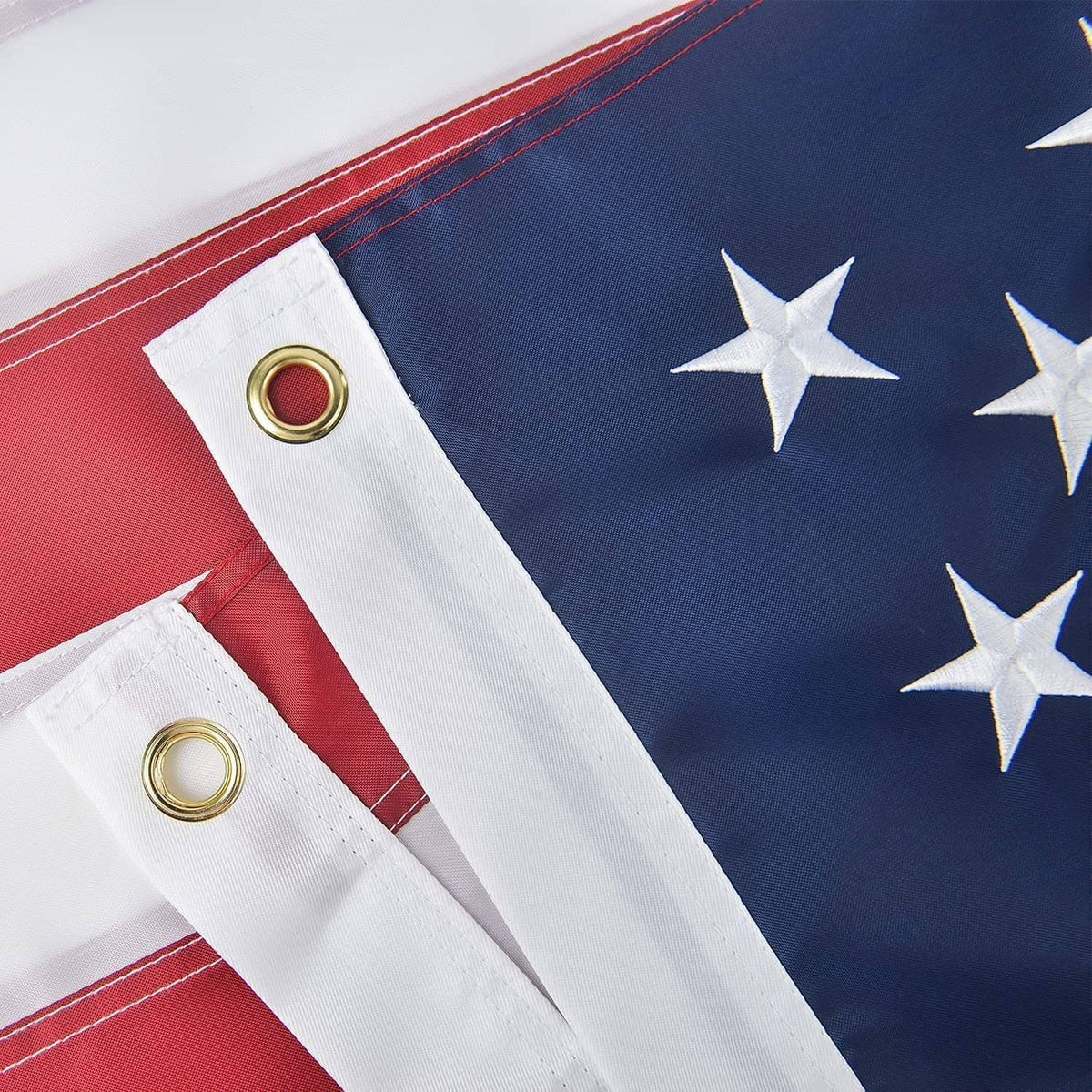 US flag with red-and-white stripes and blue field, showing brass grommets for hanging.