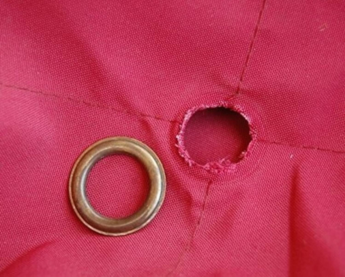 Red umbrella canopy fabric with open grommet hole and metal ring detail