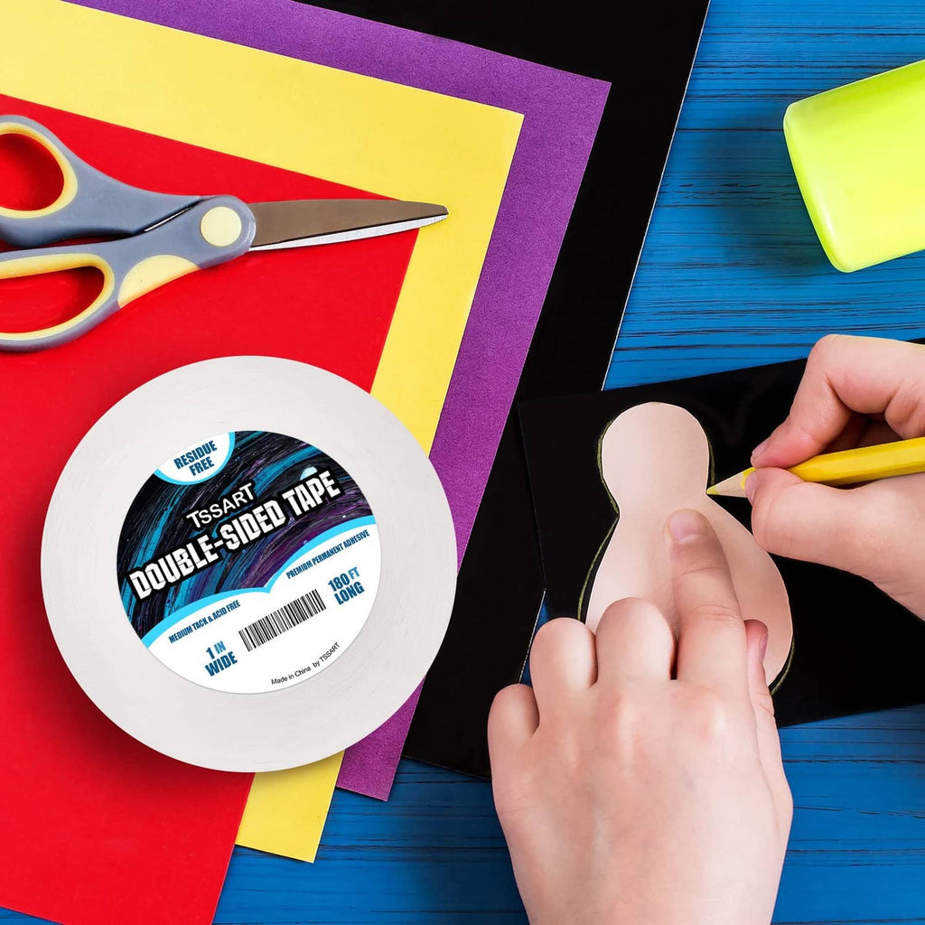 Translucent double-sided tape roll next to hands using it on paper crafts